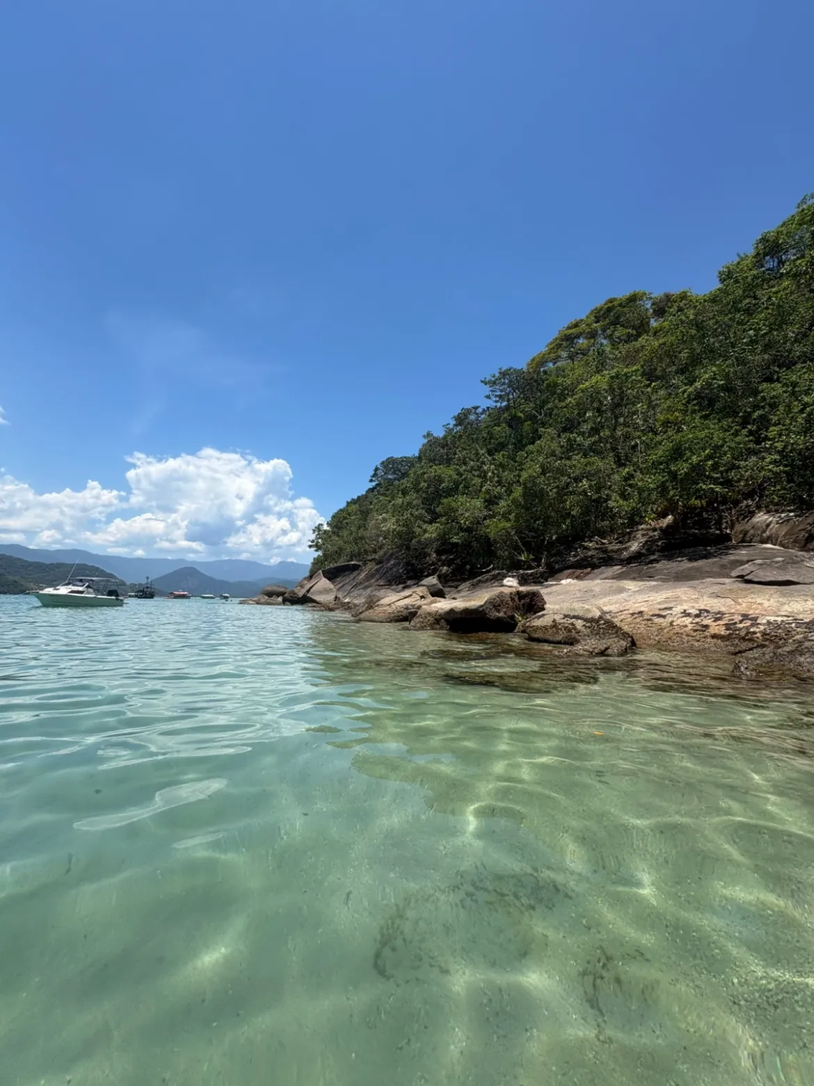 Água rasa e cristalina sobre pedras, vista de dentro do mar